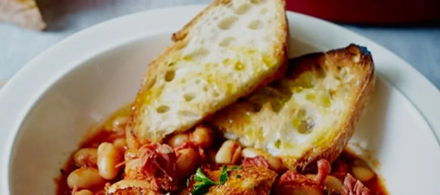 A bowl of smoky pork and Boston beans with griddled bread on top