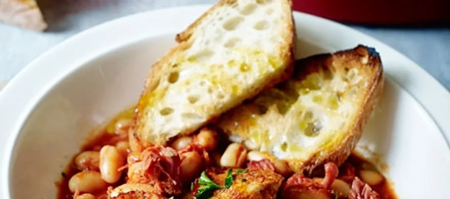 A bowl of smoky pork and Boston beans with griddled bread on top